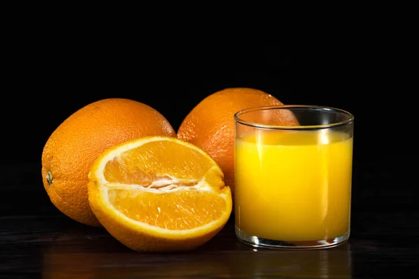 Glass of fresh orange juice and oranges on a vintage wooden background — Stock Photo, Image