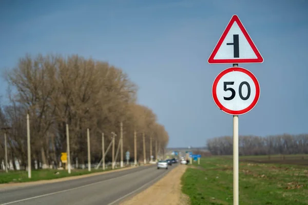 Verkehrsschilder begrenzen die Geschwindigkeit auf 50 Stundenkilometer. Die Straße biegt nach links ab Stockfoto