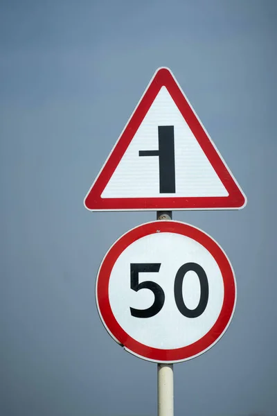 Verkehrsschilder begrenzen die Geschwindigkeit auf 70 km / h. Die Straße biegt nach links ab. Nahaufnahme lizenzfreie Stockbilder