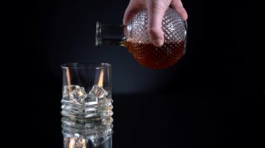 Bir adam viskiyi ağır çekimde bardağa doldurur.