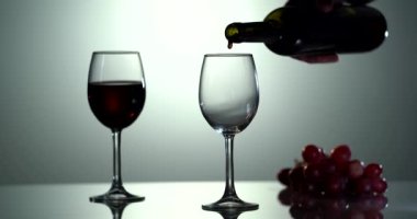 Kırmızı şarap güzel bir dalga oluşturur. Beyaz arka plandan şarap kadehi dökülüyor. Yakın plan çekim. Şişeden kadehe dökülen kırmızı şarabın 4K görüntüsü..