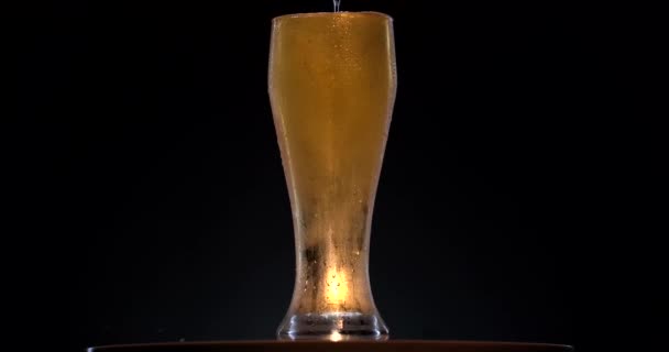 黒を基調としたライトビールでガラスの回転。ガラス、泡および泡の上昇のビールの棒。ビールのガラスはゆっくりと時計回りに回転する. — ストック動画