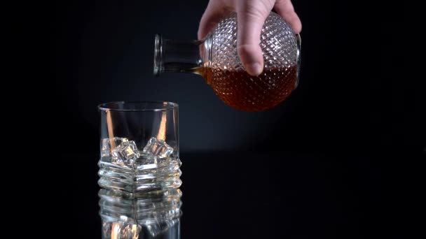 Een mensenhand giet whisky in een glas in slow motion — Stockvideo