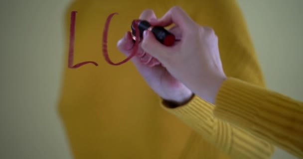 Belle main féminine écrit un message d'amour avec un sourire. Le mot amour écrit en rouge à lèvres sur la fenêtre, relation amoureuse, jolie carte vidéo Saint Valentin. La fenêtre est décorée d'un — Video