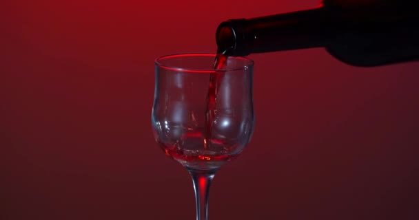 Du vin. Vin rouge coulant du col de la bouteille dans un verre de vin sur fond sombre. Du vin rose coulant de la bouteille. Vidéo 4k. Fond blanc — Video