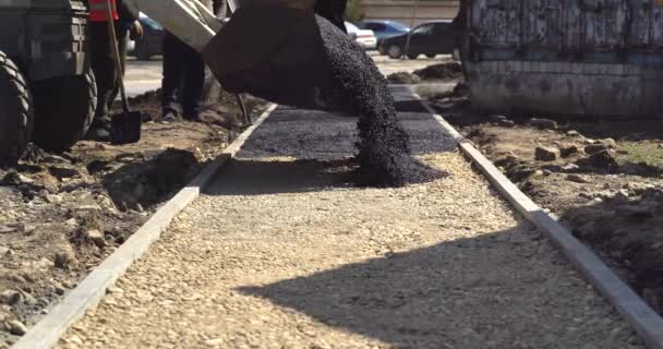 Traktor schüttet frischen Asphalt auf die Straße. Industriepflaster verlegt frischen Asphalt auf Baustelle — Stockvideo
