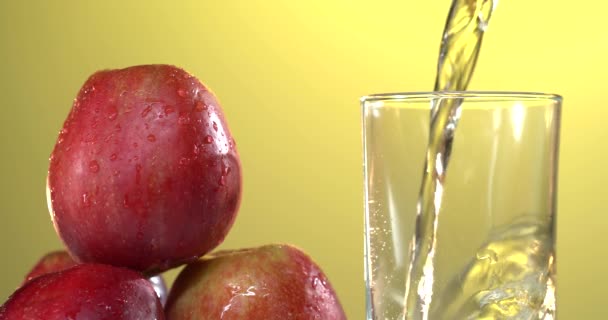 ジュースをグラスに注ぐことのクローズアップ。近くのテーブルには新鮮な赤いリンゴがあります。4kビデオ — ストック動画