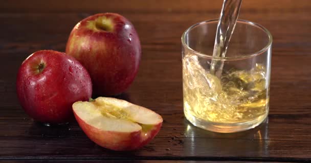 Nahaufnahme des Gießens von Saft in ein Glas. in der Nähe liegen frische rote Äpfel auf dem Tisch — Stockvideo