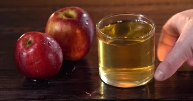 Yakın plan. Bir adamın eli çerçeveye bir bardak elma suyu koyar.