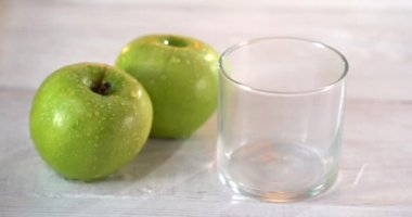 Bir bardağa meyve suyu dök. Yakınlardaki beyaz masada taze yeşil elmalar var. 4k video