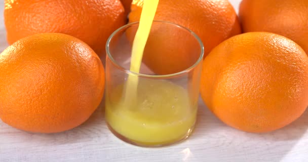 클로즈업. 오렌지 주스 를 잔에 붓는다. 근처 테이블 위에 신선 한 오렌지가 있어요 — 비디오