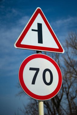 Yol işaretleri saatte 70 km hız limitini gösteriyor. Yol sola dönüyor. Çiğ çekimi kapat.