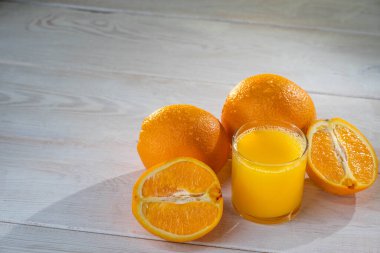 Portakal suyu ve portakallar beyaz arka planda duruyor.