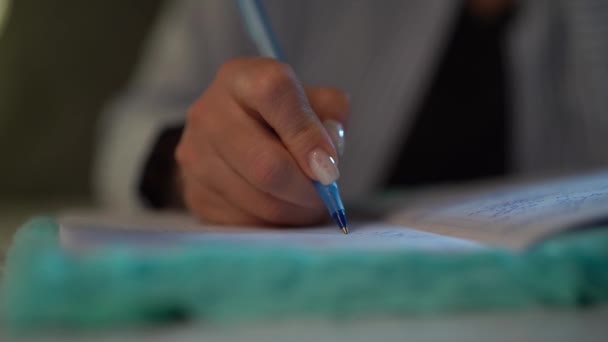 A womans hand writes with a pen in a notebook. close-up — Stock Video