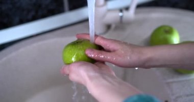 Kadın eli yeşil elmayı yıkıyor. 4k görüntü