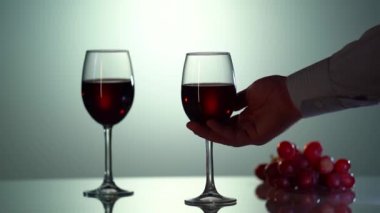 Mans silueti el ele verip yansıyan yüzeyi ile masadan bir bardak şarap alır.