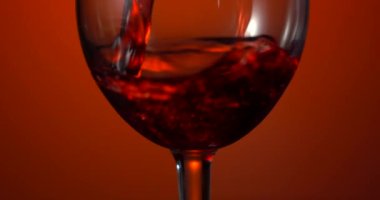 Kırmızı şarap güzel bir dalga oluşturur. Beyaz arka plandan şarap kadehi dökülüyor. Yakın plan çekim. Kırmızı şarabı kadehten kadehe yavaş yavaş dök..