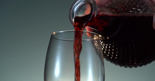 Detailní záběr náplně sklenice s červeným vínem. Nalít červené víno do poháru. Červené víno tvoří krásnou vlnu ve skle — Stock video