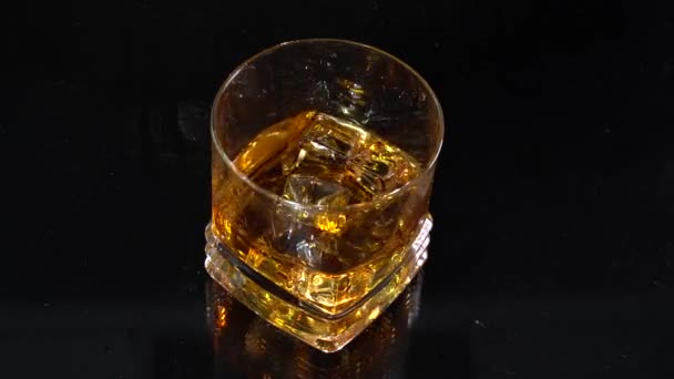 Poproszę whisky. Barman wrzuca kostki lodu do szklanki z alkoholem w zwolnionym tempie. Szkło w odbitej powierzchni. 100 fps — Wideo stockowe