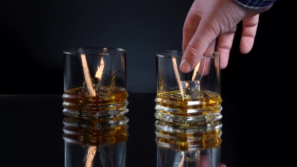 Whisky i baren. Man tar glas wirh alkohol och isbitar och clink glasögon med en annan man. Sakta i backarna. Närbild skott — Stockvideo