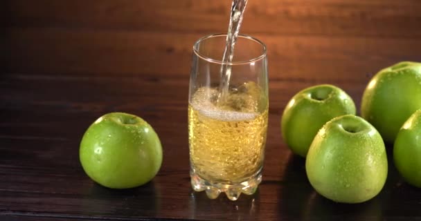 Close-up van het gieten van sap in een glas. Er liggen verse rode appels op tafel in de buurt. 4k video — Stockvideo