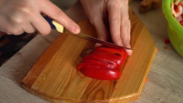 Close up shot of chefs hands cutting a fresh red bell pepper with knife on wooden board. Cooker preparing vegetarian salad in kitchen, 4k footage — Stock Video