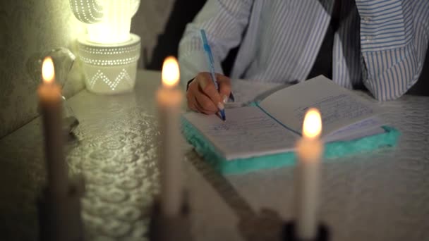 Женская рука пишет ручкой в блокноте ночью... крупным планом. 4k кадров — стоковое видео