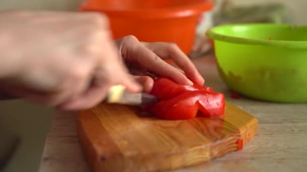 Жіночі руки використовують кухонний ніж, що ріже свіжий помідор на дерев'яній обробній дошці. Здорове харчування. Нарізаний помідор. концепція їжі. приготування вечері — стокове відео