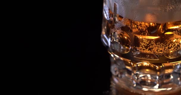 Крупним планом вміст склянки пива. Пиво повільно плаває в склянці, хвилях, бульбашках і піні . — стокове відео