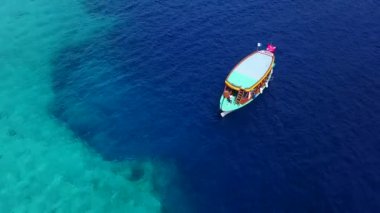 Lüks bir yat denizde yüzüyor. Turkuaz gölde seyreden lüks bir yatın havadan görünüşü. Lüks teknenin hava aracı izleme videosu. Motor Yat açık denizde seyrediyor.