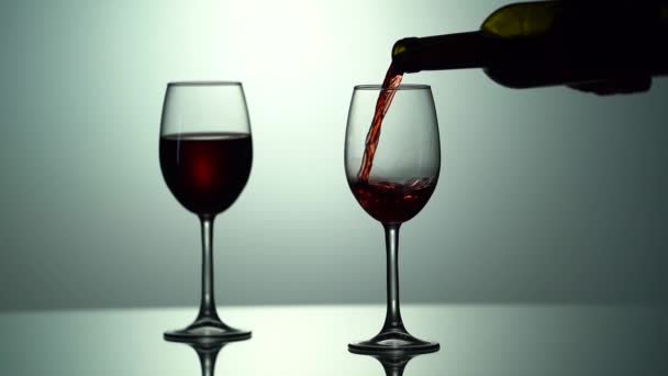 Крупним планом наповнення келихом вина червоним вином в супер повільному русі. Наливаємо червоне вино в чашку. Червоне вино формує красиву хвилю в склі — стокове відео