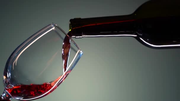 El vino tinto forma una ola hermosa. Vino vierte en copa de vino sobre fondo blanco. Primer plano de tiro. Movimiento lento de verter vino tinto de la botella en la copa. Alcohol. — Vídeo de stock