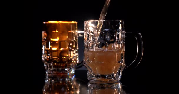 To glas håndværk øl på reflektere overflade, mørk øl og lys øl. Forfriskende glas alkohol isoleret på en træbaggrund. Barman hælder øl i glasset. Sort baggrund – Stock-video