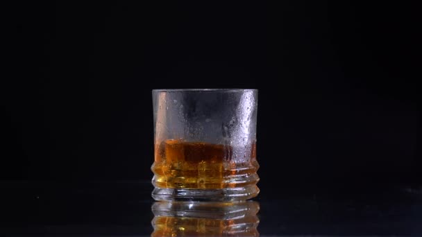Super Slow Motion Shot of csepegtető a jég, hogy az üveg Whiskey — Stock videók