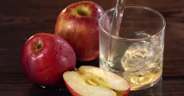Nalévání čerstvé jablečné šťávy do skla na tmavém stole — Stock video