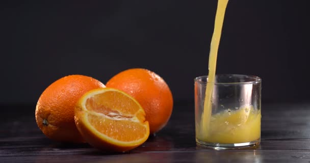 Despeje suco de laranja no copo. Fundo escuro. Sucos frescos estão em cima da mesa. Humor de verão — Vídeo de Stock