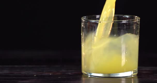 Nahaufnahme. Orangensaft wird in ein Glas gegossen. in der Nähe liegen frische Orangen auf dem Tisch — Stockvideo