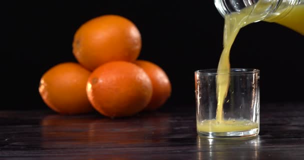 Vierte jugo de naranja en el vaso. Fondo oscuro. Los jugos frescos están sobre la mesa. Humor de verano — Vídeos de Stock