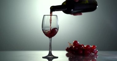 Kırmızı şarap güzel bir dalga oluşturur. Beyaz arka plandan şarap kadehi dökülüyor. Yakın plan çekim. Kırmızı şarabı kadehten kadehe yavaş yavaş dök. Siluet