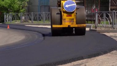 Sıkıştırıcı yeni dökülmüş asfaltı eziyor ve bir deliği onarmak için yolda sıkıştırıyor. Yeni sıcak asfaltı yuvarlayan yol silindirine yakın çekim. Yeni yerleştirilmiş bir asfalt tabakası. Yol yüzeyi onarımı.