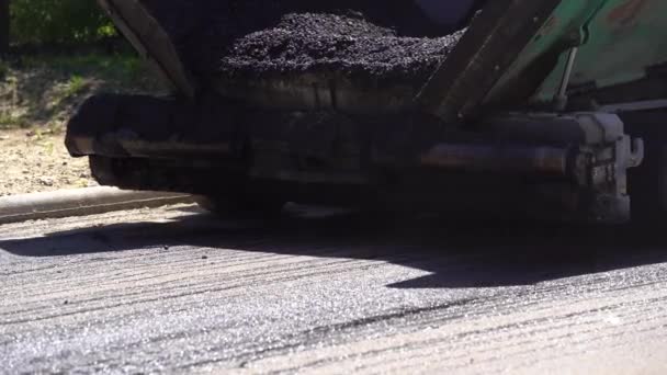 Compactor is driving over freshly loured asphalt and compresses it on the road to fix a hole. Крупный план дорожного ролика, который раскатывает новый горячий асфальт. Слой свежеуложенного асфальта. Ремонт дорожного покрытия. — стоковое видео