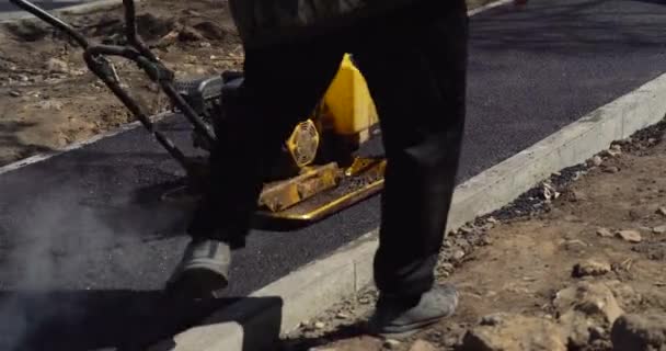 Nowy Jork, USA - 20 maja 2021: Kompaktor przejeżdża świeżo wylany asfalt i kompresuje go na drodze, aby naprawić dziurę. Zbliżenie rolki drogowej, która toczy się nowy gorący asfalt. Świeża warstwa — Wideo stockowe