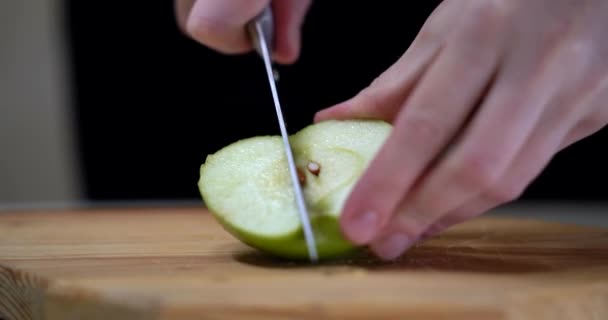 Manzana verde se encuentra a bordo, chica con manicura roja corta manzana por la mitad Primer plano. Imágenes de 4k — Vídeo de stock