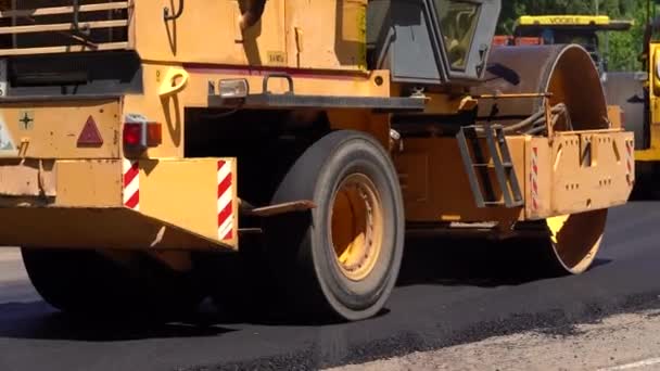 Compactor is driving over freshly poured asphalt and compresses it on the road to fix — Stock Video