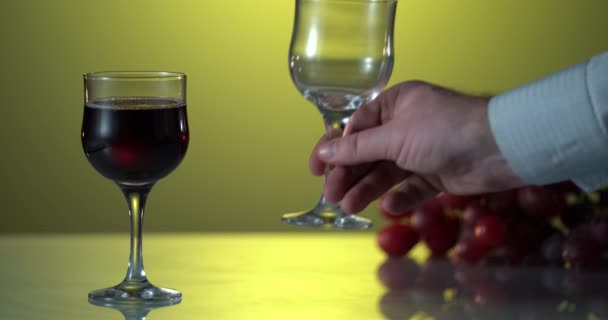 Mans hand sätta glaset för ett rött vin till bordet. Gul bakgrund — Stockvideo