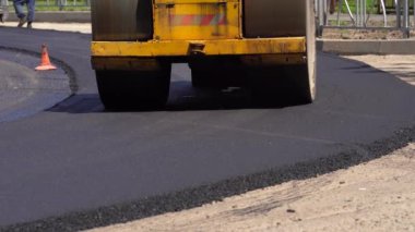 Sıkıştırıcı yeni dökülmüş asfaltı eziyor ve yolda sıkıştırıyor.