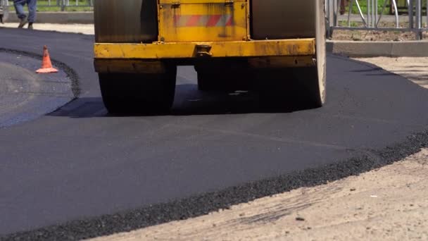 Kompaktor przejeżdża świeżo wylany asfalt i kompresuje go na drodze, aby naprawić dziurę. — Wideo stockowe