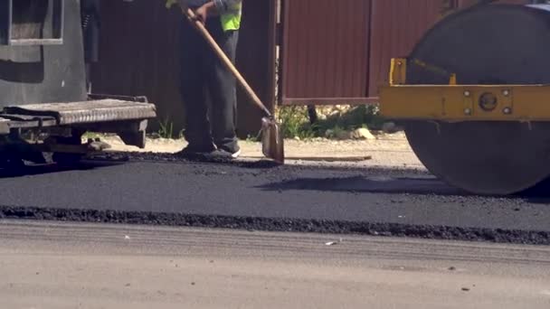 Konstruktioner Arbetstagare som arbetar på vägen. Arbetarna satte den heta asfalten. Reparation av motorvägen. Bygger en ny väg med vägreparationer. Vägvält. Tunga maskiner. — Stockvideo