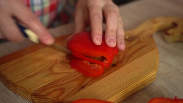 Slicing sweet peppers on a chopping board by a chef, close-up of mens hands cutting red peppers with a knife, slow motion. healthy food concept. — Stock Video