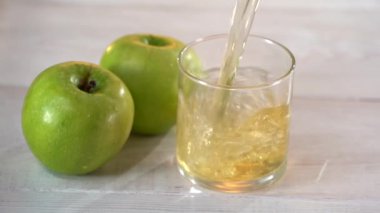 Yavaş çekimde bardağa taze elma suyu döküyorum. Güzel beyaz masa. Yeşil elmalar camın yanında.